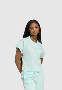 Camiseta de color verde menta claro con mangas cortas, ajuste holgado, escote redondo y logo de la marca sutil. Tejido suave con una textura lisa.