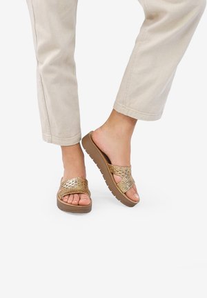 Gold slide sandals with textured woven upper, soft footbed, and rubber outsole. Designed with a cross strap and open toe for breathability.