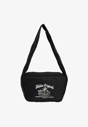 Bolso negro de hombro hecho de tela con una textura suave. Cuenta con un gran logo frontal en blanco. Tiene una sola correa ancha para llevar.