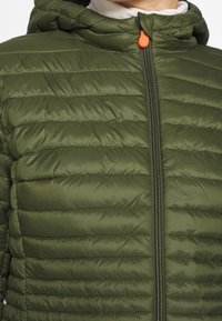 Doudoune verte olive avec capuche, présentant une texture matelassée horizontale, une fermeture éclair à l'avant et un tirette de fermeture éclair orange.