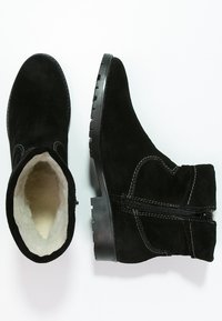 Botas negras de ante hasta el tobillo con una superficie texturizada, que cuentan con un suave forro de piel de pelo, cremallera lateral y una suela de goma negra resistente.