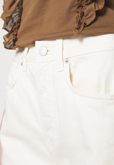 Hvite jeans med høy midje, som har en foran knappelukking, sidelommer og svak diagonal tekstur.