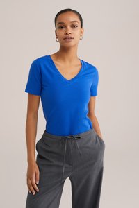 T-shirt bleu à col en V en tissu doux, à manches courtes, assorti à un pantalon gris à rayures avec une taille élastique et un cordon de serrage.