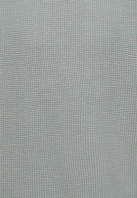 Lysegråt stof med en lille, ensartet vafletvævet struktur, der danner et gittermønster over overfladen.