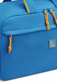 Borsa da viaggio blu realizzata in nylon testurizzato, con componenti gialli, maniglie e una toppa con logo. Design rettangolare compatto.