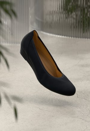 Bailarina negra con punta redondeada, parte superior lisa y mate, y plantilla ligeramente acolchada en color beige. Diseño simple sin elementos metálicos visibles.