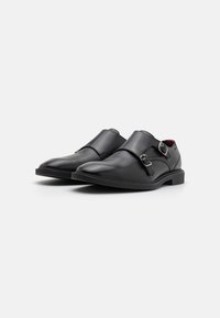 Zwarte leren schoenen met een elegant ontwerp, dubbele gespaccenten en een gladde textuur. Lage hak met een ronde neus.