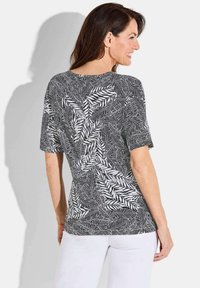 Korte mouw t-shirt in zwart en wit met bladpatroon. Gemaakt van lichtgewicht stof, heeft een comfortabele pasvorm en een gebogen zoom.