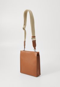 Brown leather handbag with a textured surface, rectangular shape, and adjustable woven strap in beige, featuring silver hardware accents.
