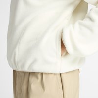 White fleece pullover with side pockets, featuring a soft texture and relaxed fit. Combines with beige, loose-fitting pants.