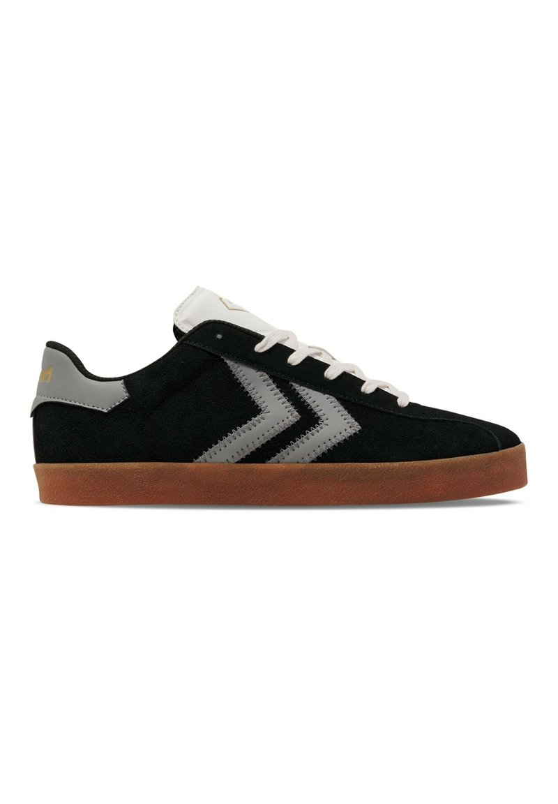 Zwarte suède sneaker met een bruine zool, witte veters en grijze chevronstrepen aan de zijkant, zijaanzicht weergegeven.