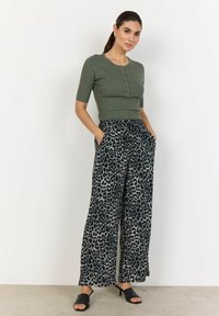 Olive green ribbed short-sleeve top with buttons, paired with wide-leg leopard print pants in gray and black. Black open-toe heeled mules.