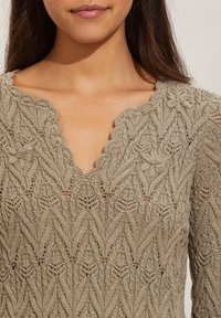 Maglione lavorato a maglia in taupe, con scollatura a V ondulata, accenti floreali e un motivo a punto aperto e testurizzato su tutta la superficie.