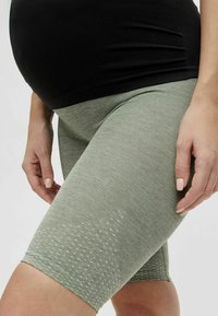 Graviditetscykelshorts i ljusgrön ribbad tyg med ett strukturerat mönster. Längd till mitten av låret med en bekväm midja.