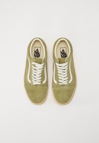 Groene suède sneakers met witte veters, voorzien van een witte zijstreep en een beige rubberen zool. Branding zichtbaar op de binnenzool.