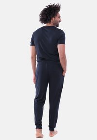 Svart lounge-set med kortärmad tröja och byxor med elastisk midja. Mjukt tyg med avslappnad passform, fickor på sidorna.