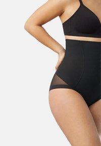 Bragas negras de tiro alto con paneles laterales de malla. Fabricadas con un tejido elástico, presentan un diseño ajustado y suave.