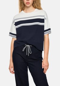 Navy and white striped short-sleeve t-shirt with a relaxed fit, paired with dark denim pants featuring a drawstring waist.