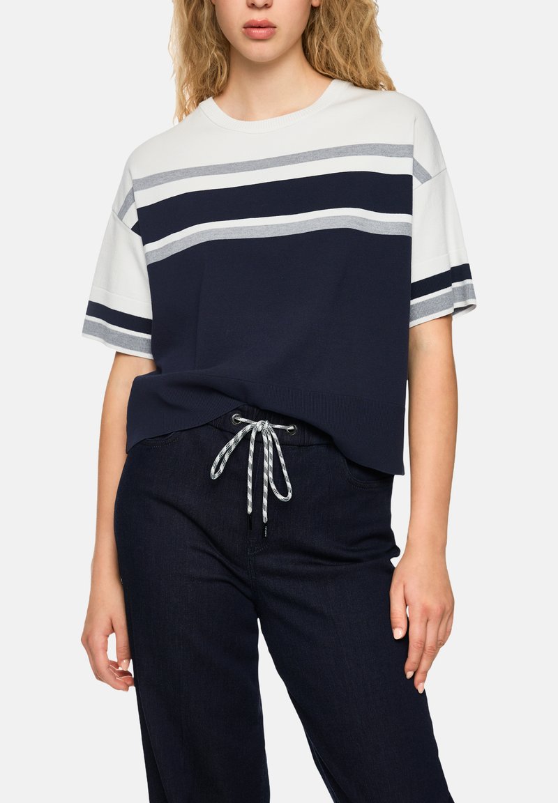 Navy and white striped short-sleeve t-shirt with a relaxed fit, paired with dark denim pants featuring a drawstring waist.