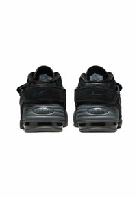 Svarta sportskor med en jämn yta och mockadetaljer, en bakre rem och en påtaglig sula med luftkuddar.