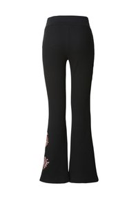 Pantalon noir évasé à côtes avec une ceinture ajustée et une broderie florale sur le bas des jambes. Le matériau semble texturé et extensible.