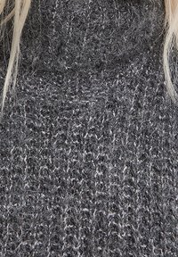 Golf in maglia a colletto alto di colore grigio scuro con una finitura testurizzata e leggermente pelosa, arricchita da fili di grigio chiaro in contrasto sparsi nel tessuto.