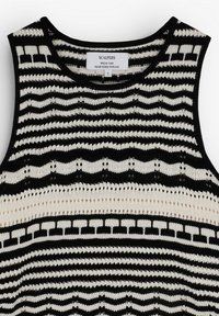 Haut sans manches en maille noir et blanc avec des rayures horizontales, des motifs géométriques et festonnés, et un col rond.