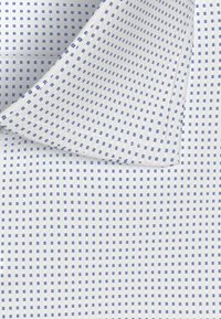 Witte gestructureerde stof met kleine blauwe patronen, voorzien van een kraag en netjes gestikte randen. Zacht katoenmateriaal weergegeven in close-up.