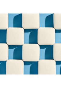 Square, white soap bars with a smooth texture, featuring a subtle embossed elephant design, arranged on a blue background.