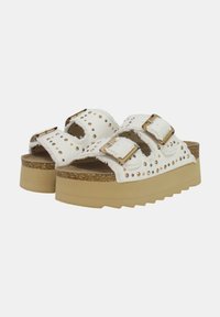Sandalias de plataforma blancas con dos correas de hebilla, detalles con tachuelas a lo largo de los bordes y una plantilla de corcho texturizada con una suela de goma beige.