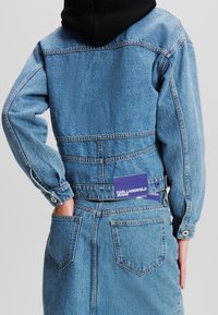 Jeansjacka i ljusblått med en avslappnad passform. Har lång ärm och två bakfickor. Etikett visar "KARL LAGERFELD JEANS."