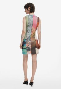 Ärmelloses Kleid mit einer taillierten Silhouette, das ein mehrfarbiges Muster, durchsichtige Abschnitte und eine glatte Textur aufweist. Schwarze Akzente entlang der Nähte.