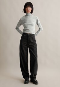 Grijze coltrui gecombineerd met hoge taille zwarte wijde jeans en zwarte platform schoenen, met een gladde textuur en een minimalistisch ontwerp.