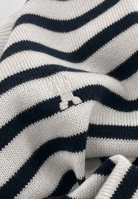 Knitted sweater with horizontal navy and white stripes; features a small white embroidered logo resembling scissors. Soft, textured fabric.