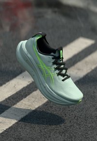 Světlé zelené běžecké boty s texturovaným svrškem, černými akcenty a reflexními detaily. Mají polstrovanou podrážku a integrované tkaničky.