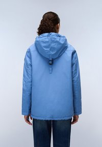 Light blue hooded jacket with a cinched neck, featuring long sleeves and a relaxed fit, paired with dark blue denim jeans.