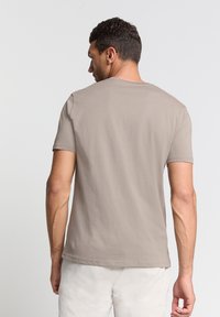 Korte mouwen, ronde hals t-shirt in lichtbeige katoen. Gladde textuur zonder zichtbare patronen. Eenvoudig, klassiek ontwerp.