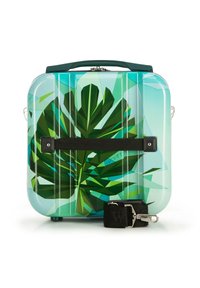 Valigia rigida con un vivace motivo a foglie verdi, esterno trasparente blu, cinturino nero e maniglie doppie sopra e ai lati.