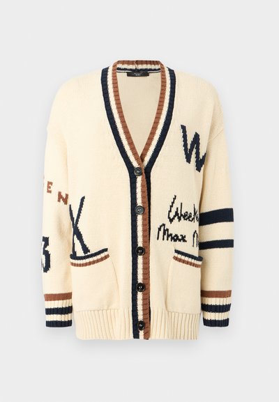 Κρεμ πλεκτή ζακέτα με μαύρα κουμπιά, καφέ και ναυτικό ριγέ περιθώριο, μπροστινές τσέπες και αφηρημένα σχέδια γραμμάτων και αριθμών στα μανίκια και το σώμα.