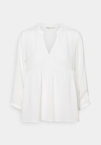 Blouse blanche à col en V, taille froncée et manches longues. Des rayures verticales texturées ajoutent du détail, avec des poignets retroussés aux manches.