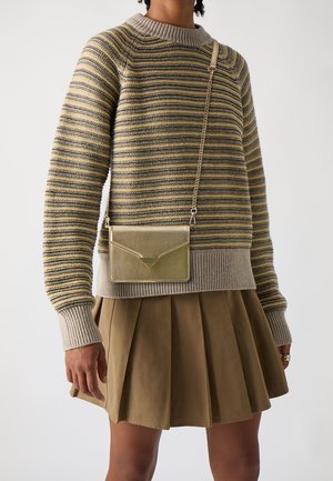 Maglione a righe beige e grigio con polsini a coste; gonna plissettata oliva; piccola borsa a tracolla dorata con finitura texturizzata e dettaglio triangolare.