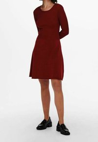 Abito a maglia a costine di un profondo rosso, con scollatura a girocollo e maniche lunghe. Design a A con una consistenza morbida e liscia e lunghezza fino a metà coscia.