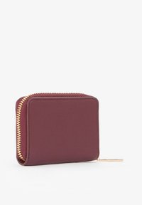 Portafoglio in pelle bordeaux con cerniera dorata, forma rettangolare, texture liscia e piccolo cursore della cerniera sul lato.