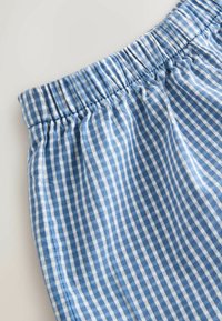 Tissu à motif vichy bleu et blanc avec une ceinture élastique, probablement une partie d'un vêtement comme un pantalon ou un short.