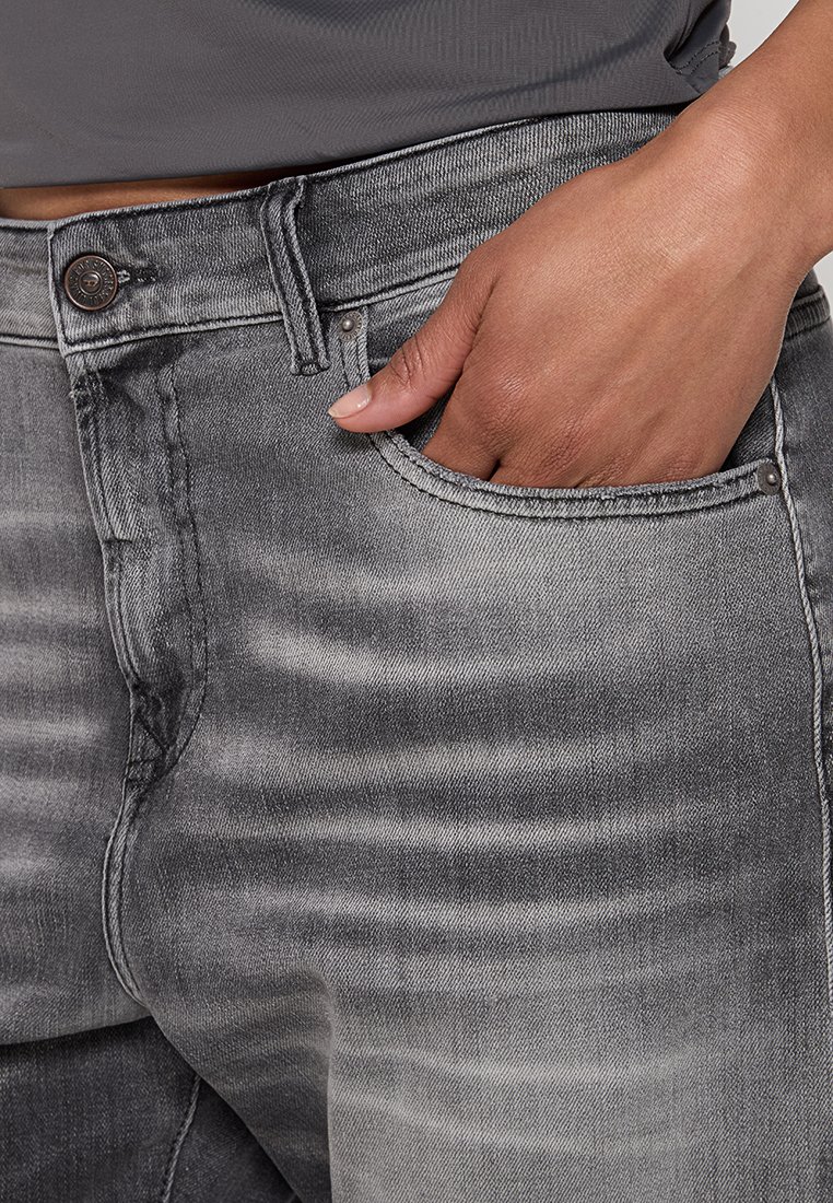 Jeans in denim grigio con un design sbiadito, stile a cinque tasche e chiusura con bottone in metallo, con cuciture visibili e una texture liscia.