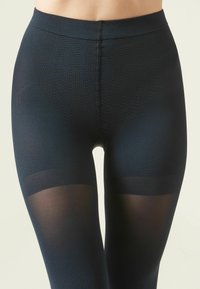 Sorte leggings med et struktureret design, en glat talje og delvist gennemsigtige detaljer nær nederste ben.