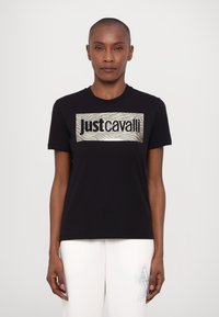 Svart t-skjorte med et rektangulært metallisk grafisk mønster med zebramønster og teksten "Just Cavalli." Korte ermer, rund halsutskjæring, avslappet passform.
