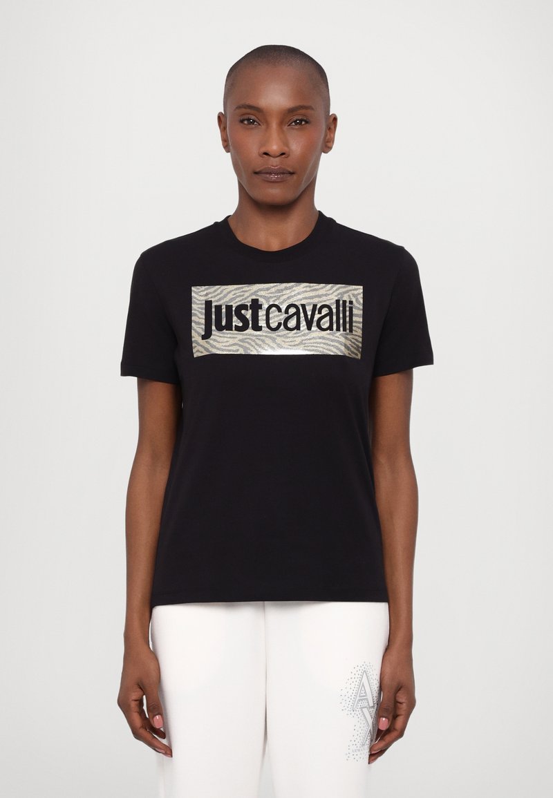 Svart t-skjorte med et rektangulært metallisk grafisk mønster med zebramønster og teksten "Just Cavalli." Korte ermer, rund halsutskjæring, avslappet passform.
