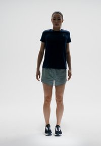 Conjunto deportivo que incluye una camiseta de manga corta azul oscura y unos pantalones cortos gris claro. Zapatillas deportivas negras. Diseño simple y estilizado.