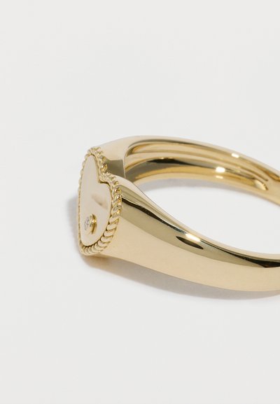 Prsteň v tvare srdca v zlatom tóne s hladkým povrchom, textúrovaným okrajom pripomínajúcim šnúru a malým okrúhlym akcentovým kameňom.